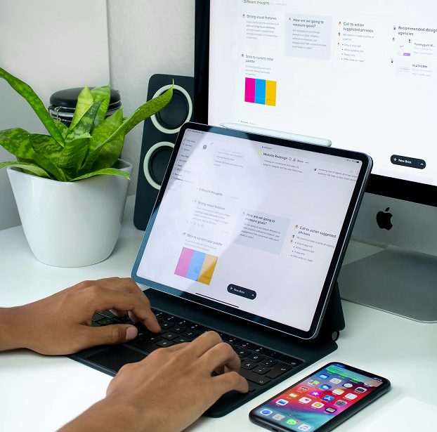 Someone typing on their laptop with a phone next to it